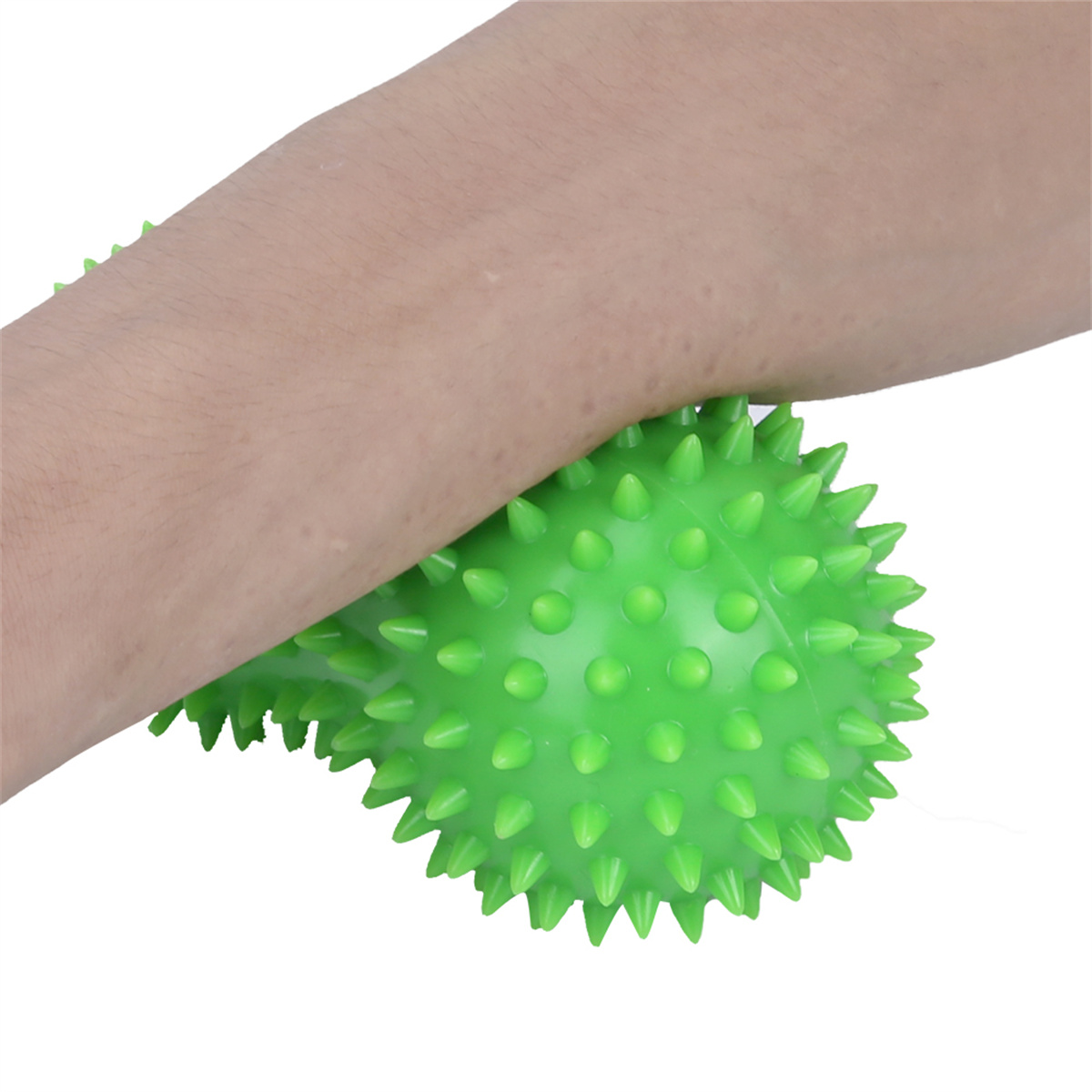 Grüner, stacheliger Massageball wird gegen einen Arm gedrückt, weißer Hintergrund.