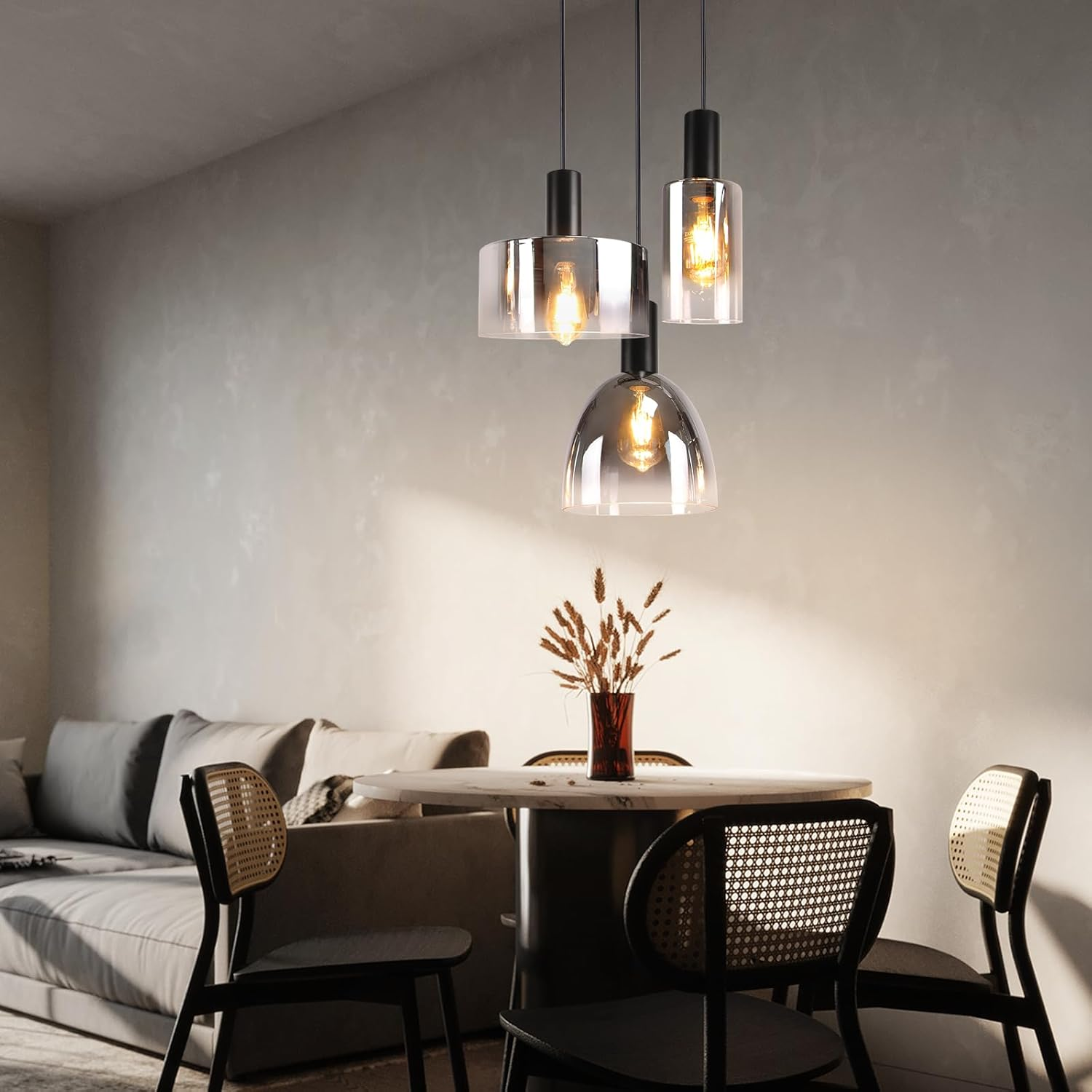Esszimmer mit Pendelleuchten, Tisch mit Vase mit Trockenblumen und Stühlen.
