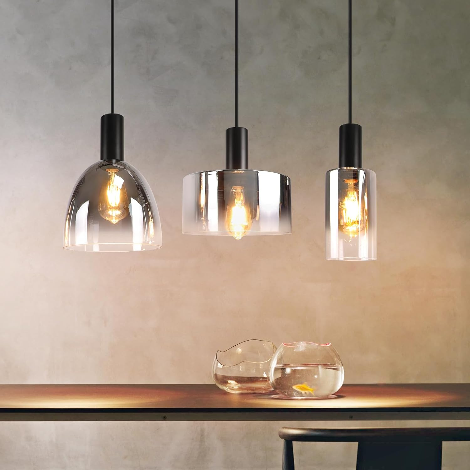 Drei Pendelleuchten mit Glasschirmen hängen über einem Holztisch mit zwei Schalen.