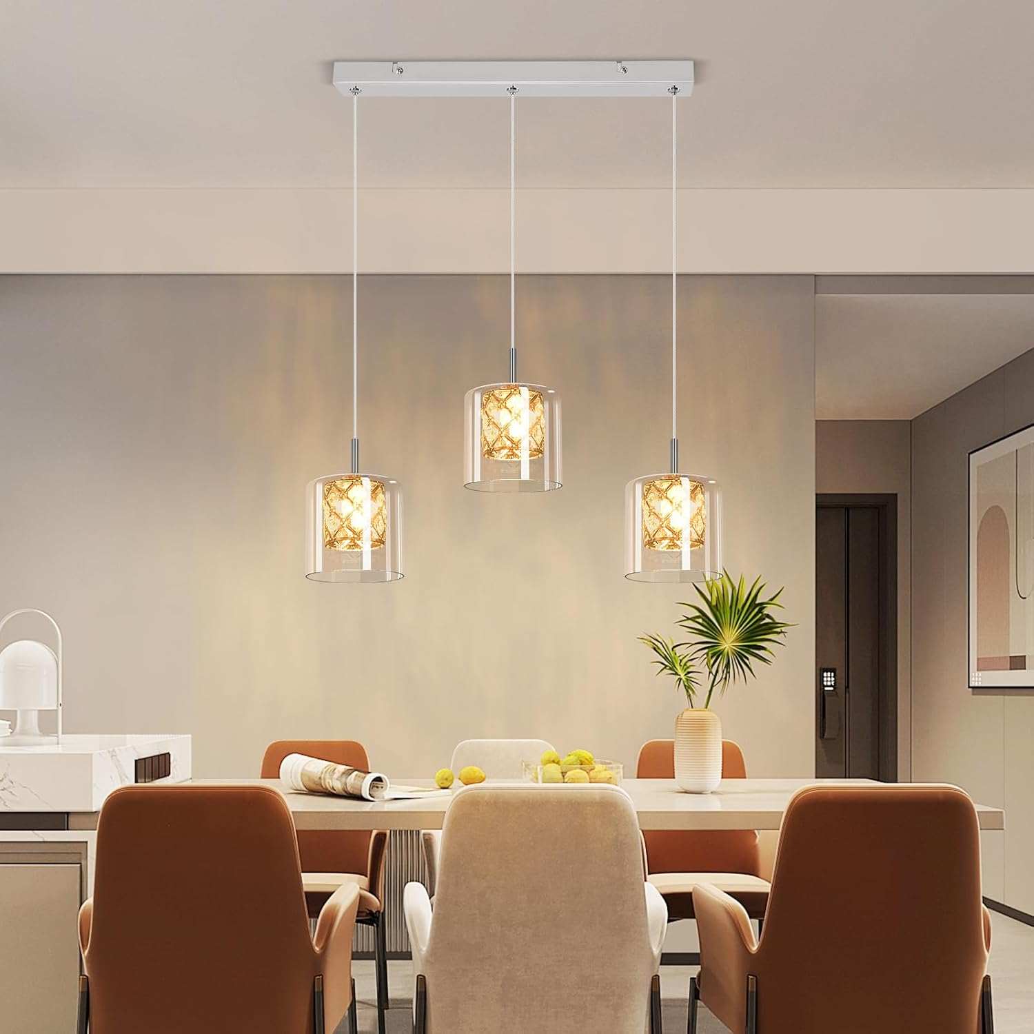 Drei Pendelleuchten mit Glasschirmen in einem Esszimmer. Braune Stühle sind sichtbar.
