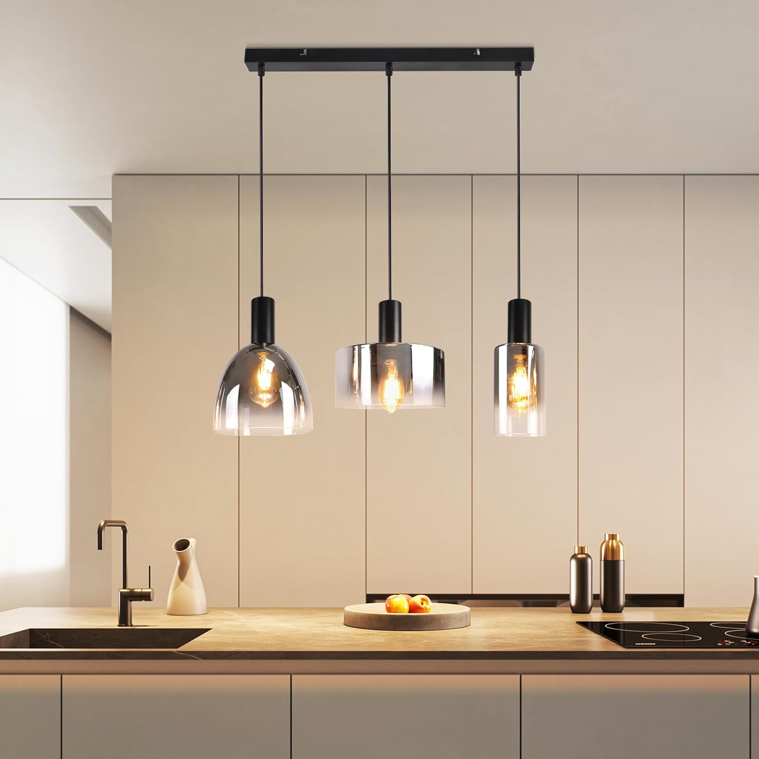 Drei Pendelleuchten mit Glasschirmen, die in einer Küche über einer Holz-Arbeitsplatte hängen.