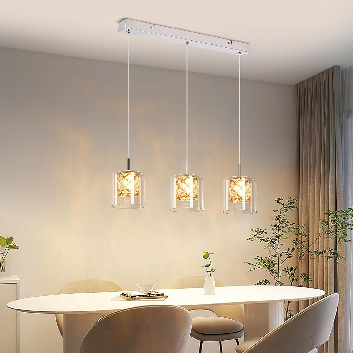Drei Pendelleuchten mit Glasschirmen hängen über einem weißen Tisch. Die Schirme haben ein goldenes Muster innen.