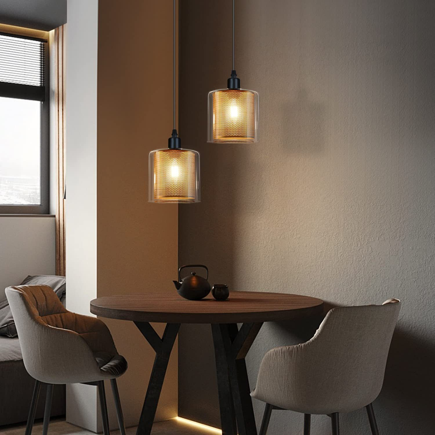 Zwei Pendelleuchten hängen über einem Tisch. Die Leuchten haben ein Metallgitter-Design mit warmem Glühen.