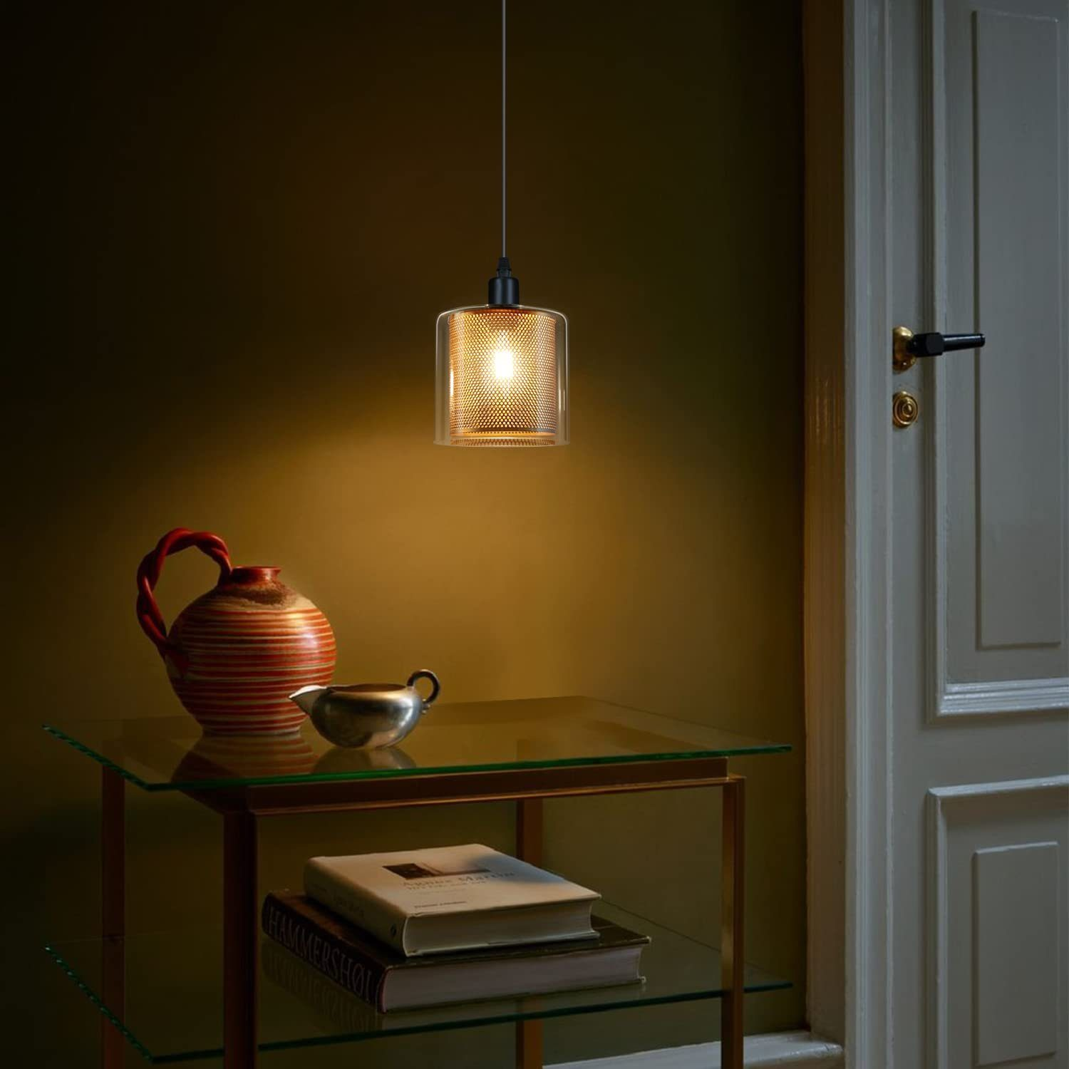 Zimmer mit Hängelampe, Tisch, Vase und Büchern. Dunkelgrüne Wand und geschlossene Tür.