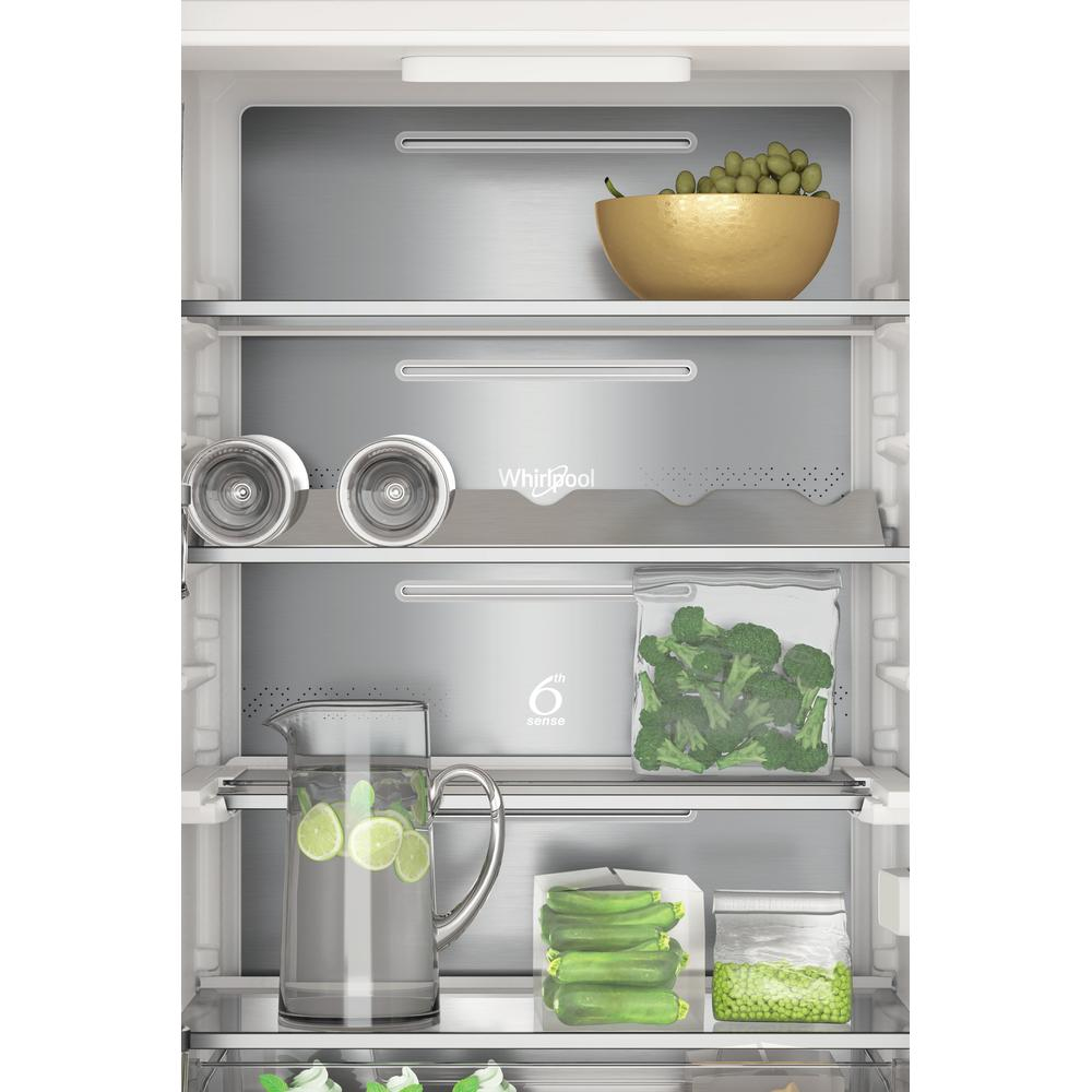 Interno del frigorifero con ripiani di cibo: uva, broccoli, piselli e limoni.