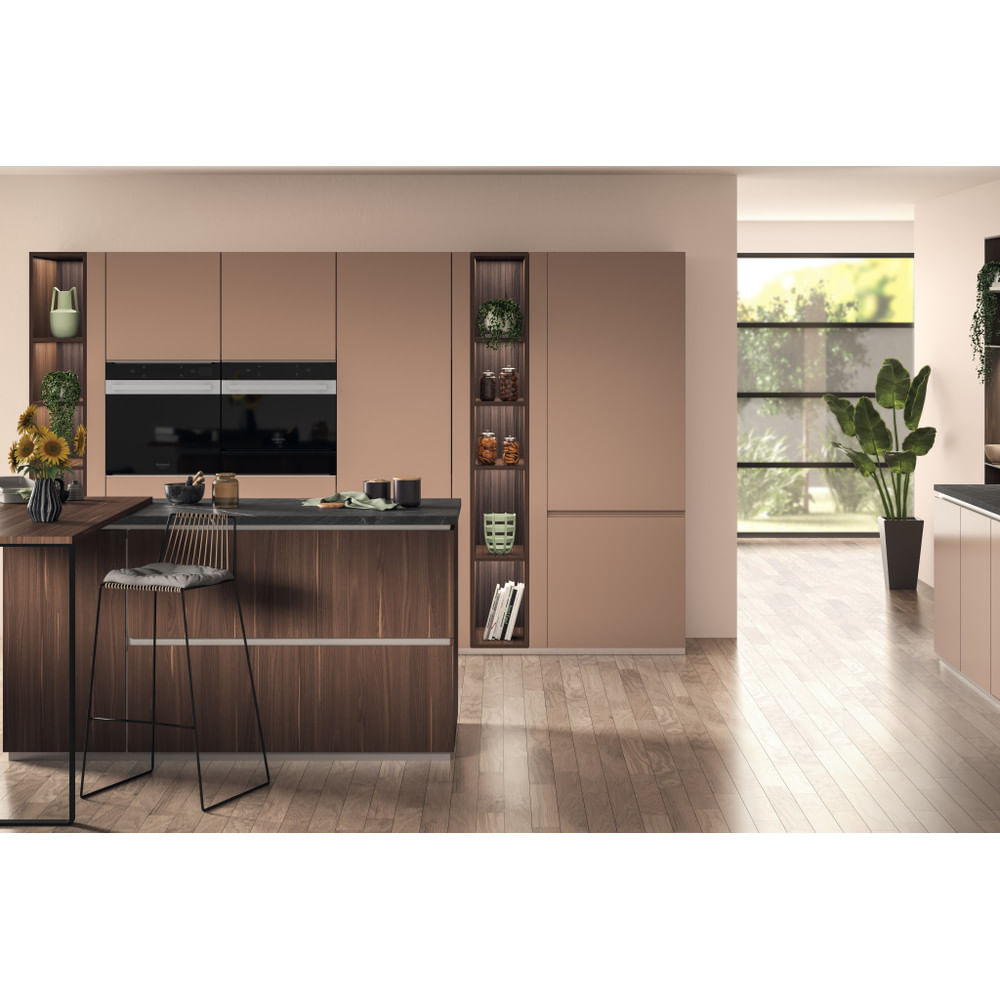 Cucina moderna con mobili marroni, isola e elettrodomestici in acciaio inox. Pavimento in legno e finestra grande.