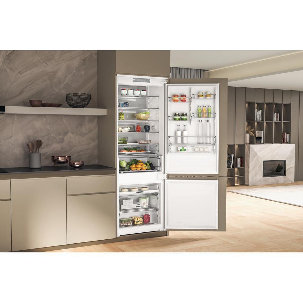 Una cucina moderna con frigorifero aperto. Il frigo contiene cibo, e un camino è sullo sfondo.