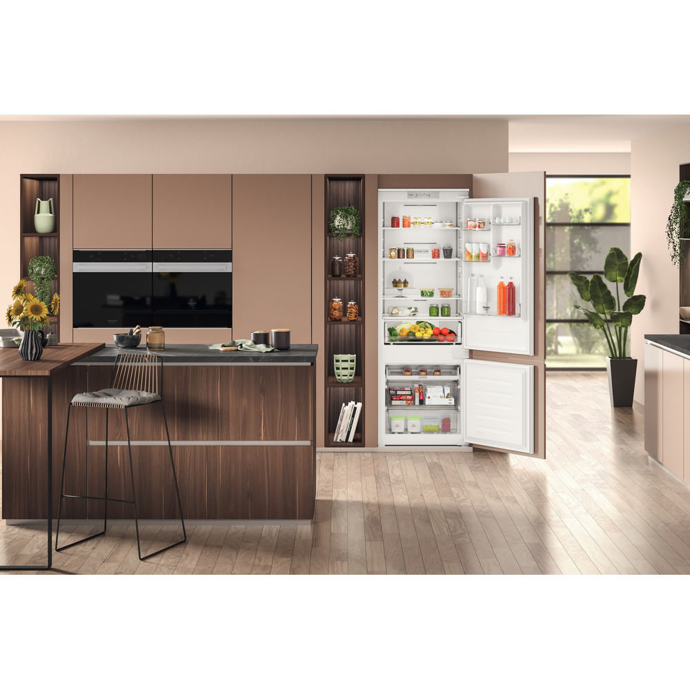 Cucina moderna con frigorifero aperto. Cibo all'interno. Isola con sgabello a sinistra. Pavimento in legno.