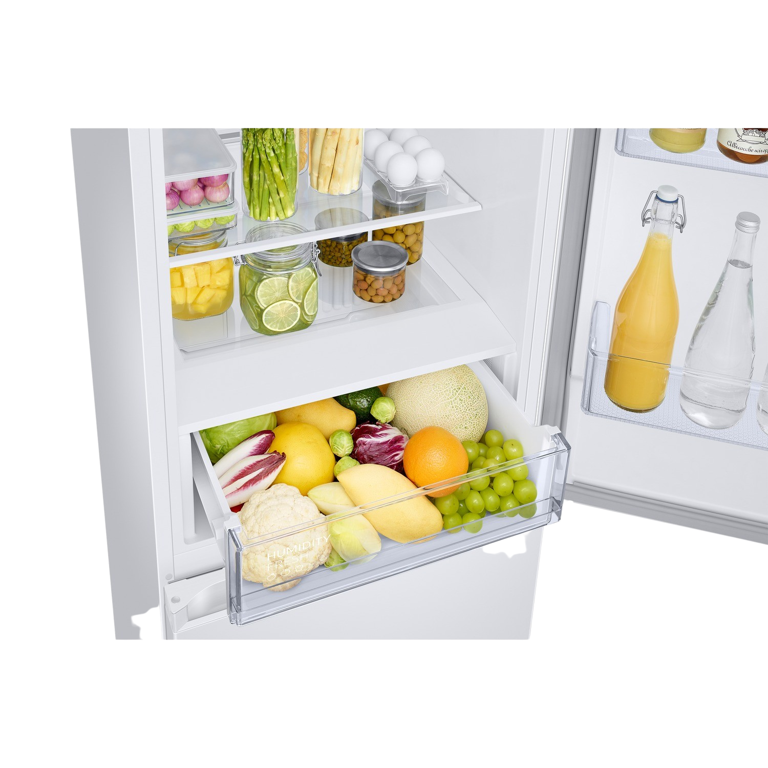 Open white fridge. Contains fruits, vegetables, and jars. Drawer is half-opened.
