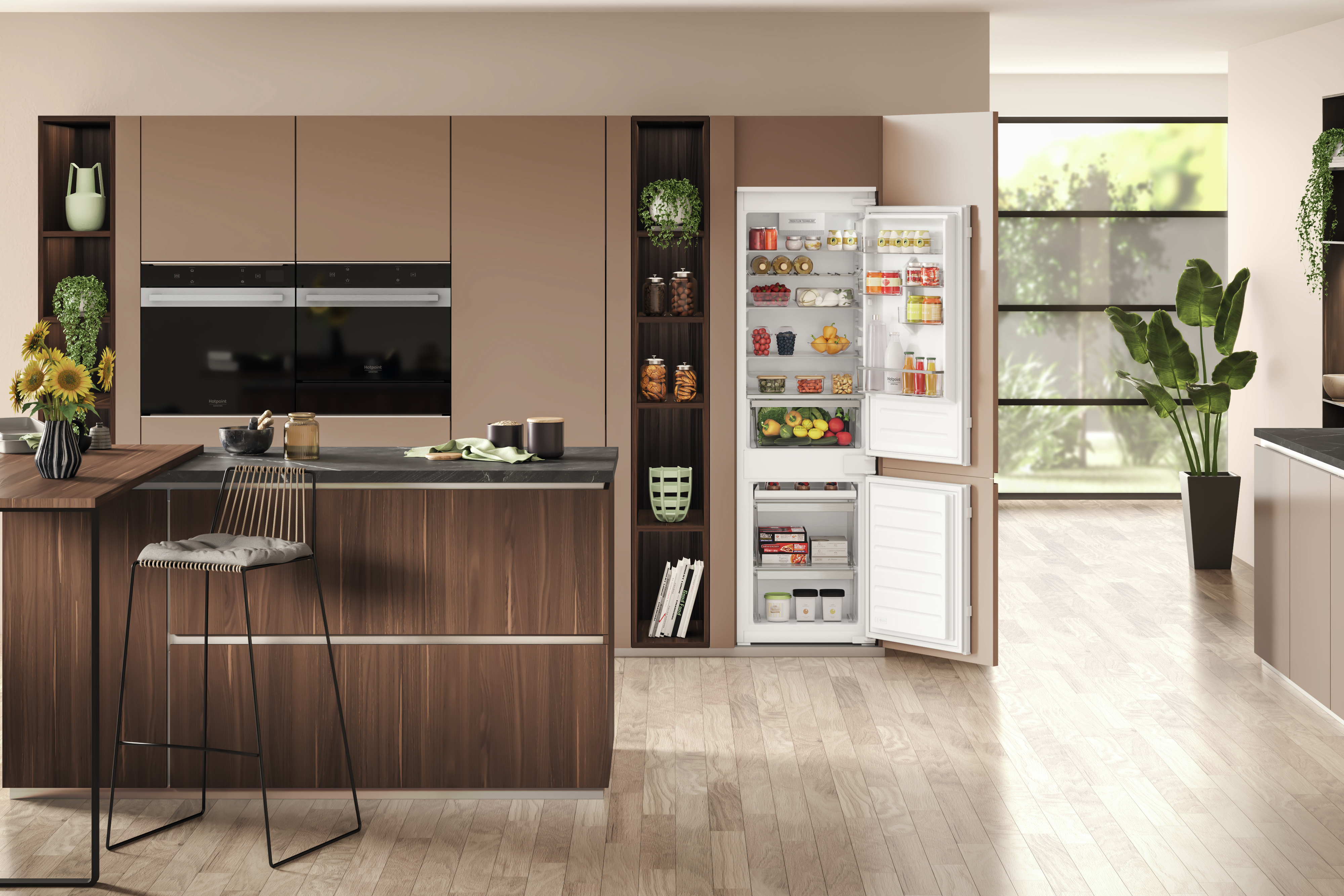 Interno cucina con frigorifero aperto. Bancone, armadi e piante visibili.