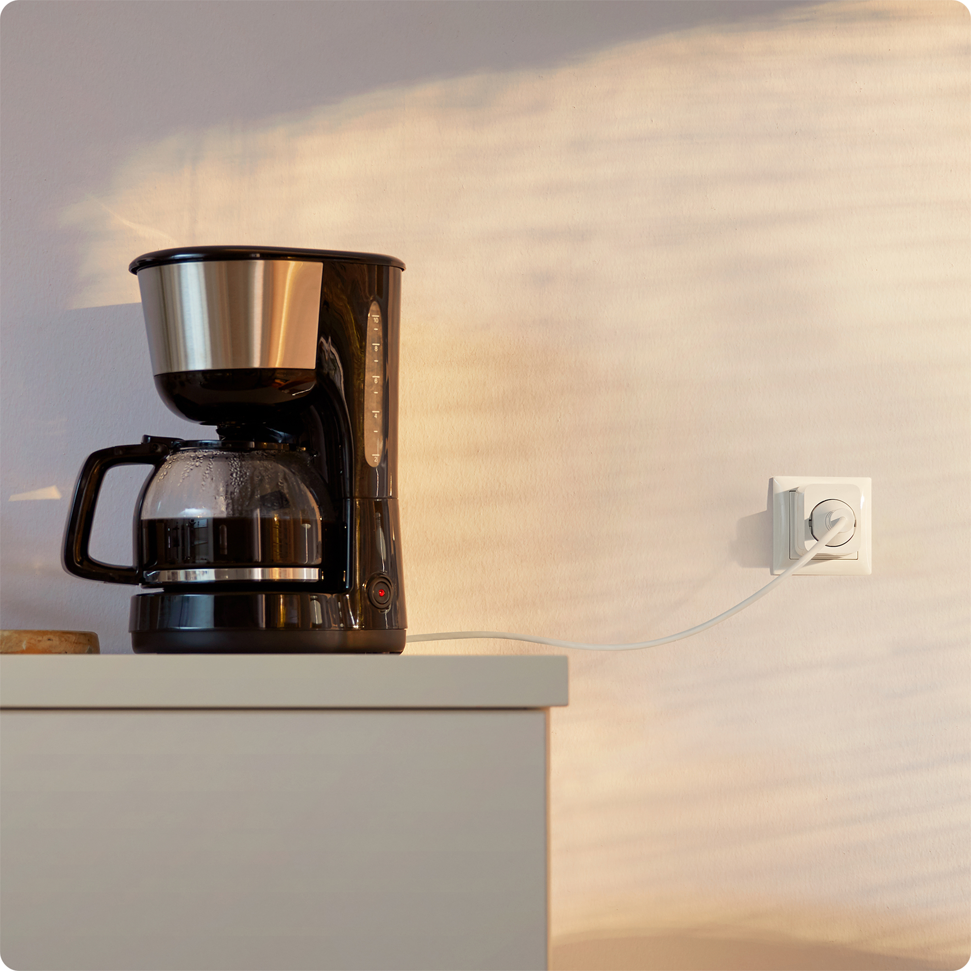Koffiezetapparaat met een glazen kan en een zwarte behuizing. Het koffiezetapparaat is aangesloten.