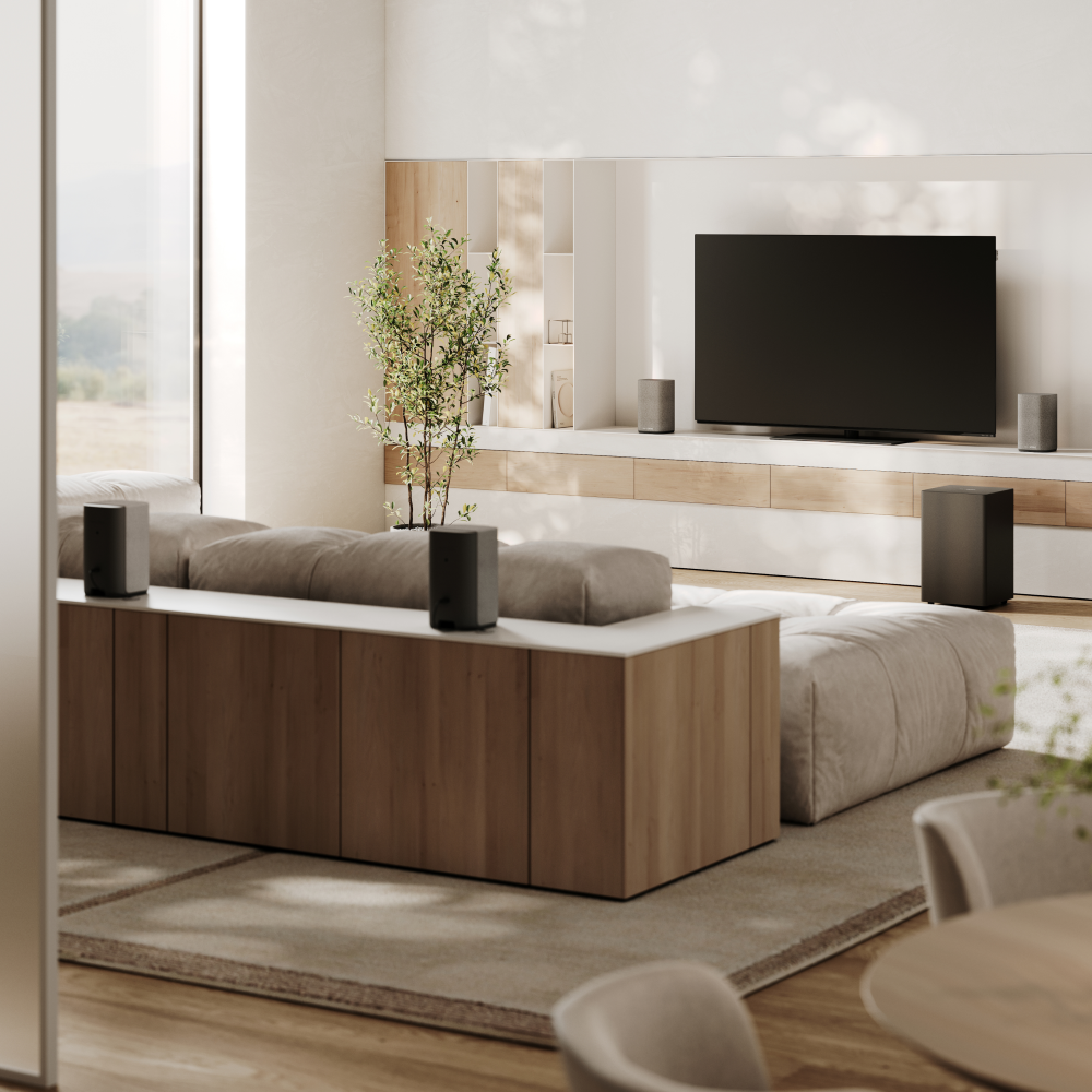 Modernes Wohnzimmer mit großem Fernseher, schwarzen Lautsprechern, hellem Holzschrank und grauem Sofa.