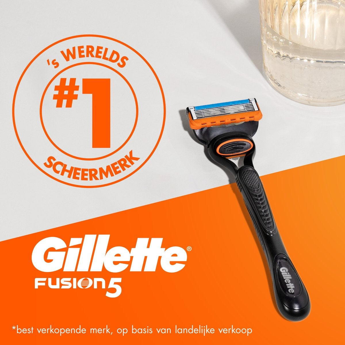 Gillette Fusion5 razor with black handle, orange accents, and a water glass in background.