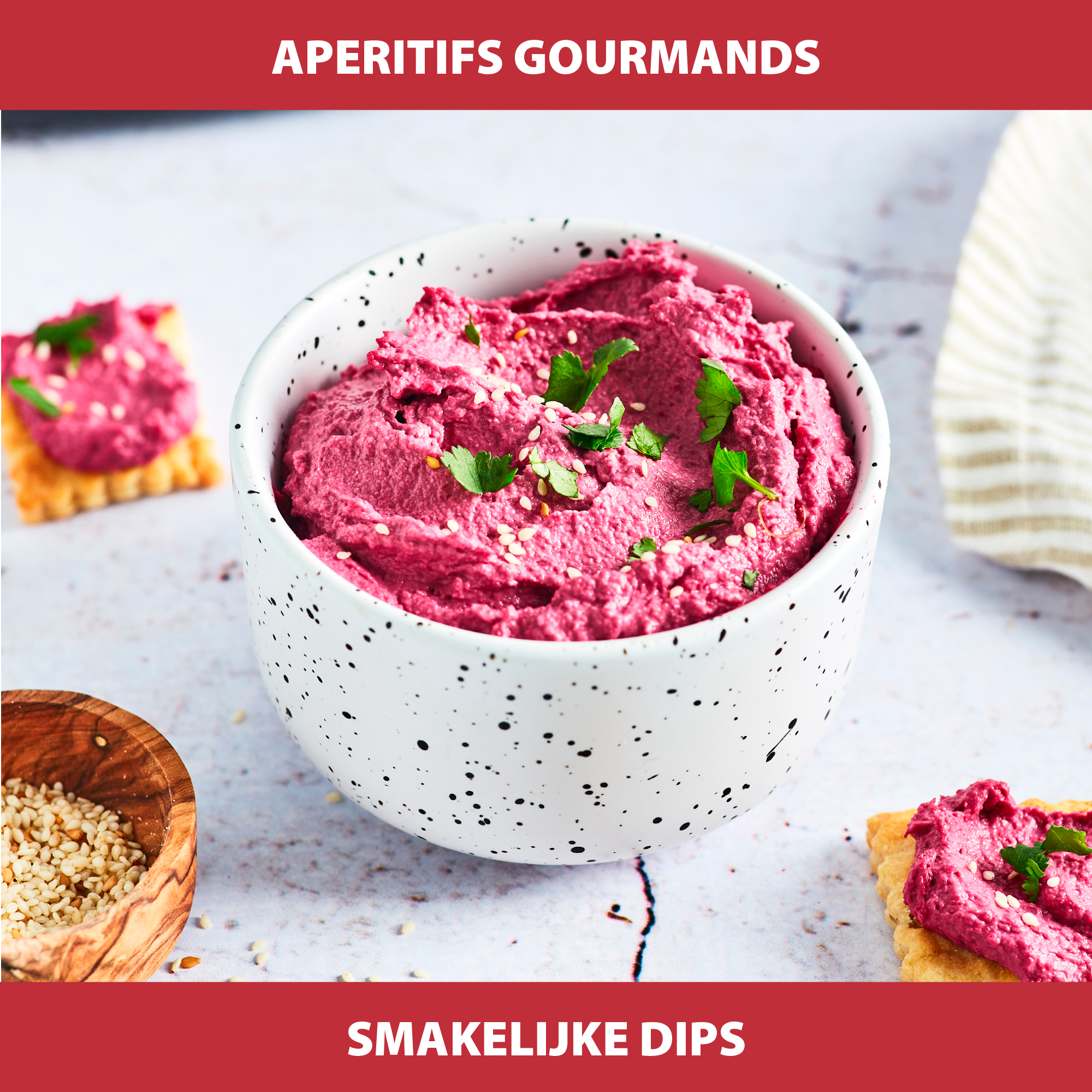 Un bol de trempette rose garni de graines de sésame et de persil, des craquelins avec de la trempette et un petit bol de graines de sésame.
