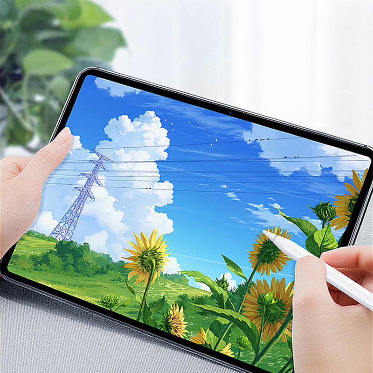 Tablet met een zonnebloemveld en een hoogspanningslijn afgebeeld op het scherm. Een hand houdt een stylus vast.