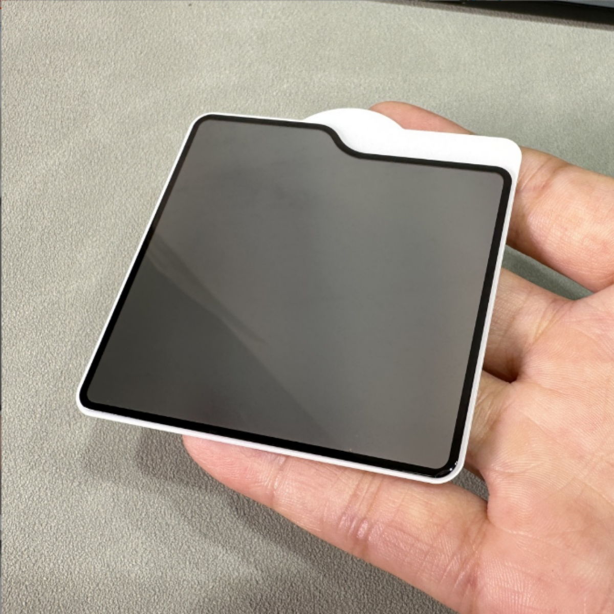 Een privacy screenprotector voor een telefoon, tegen een lichtgrijze achtergrond.
