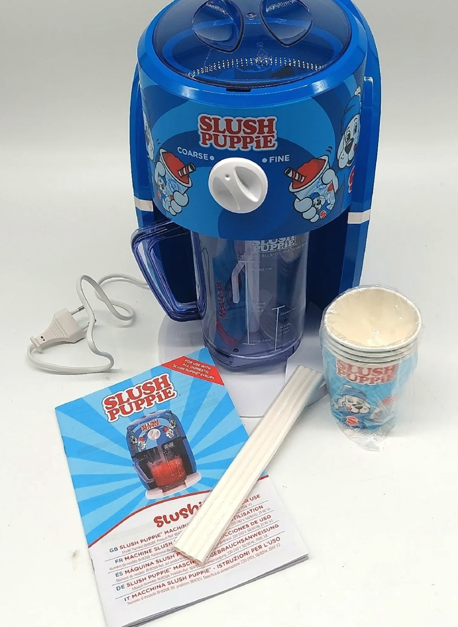 Blue Slush Puppie machine, cups, and a booklet on a white surface.