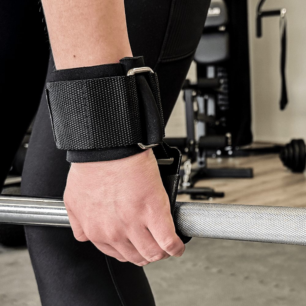 De hand van een persoon met polsbandjes houdt een halter vast. Gym interieur op de achtergrond.