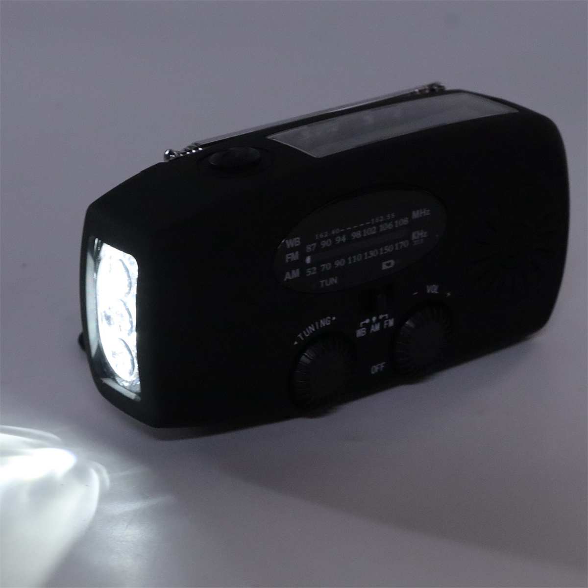 Schwarzes Radio mit Taschenlampe. Mit Drehknöpfen und Lautsprecher auf weißer Oberfläche.