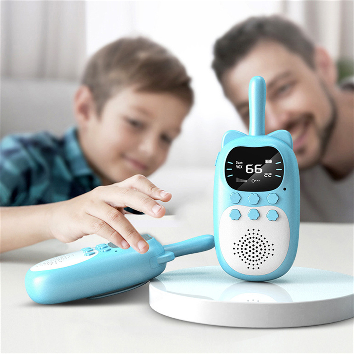 Zwei blaue Walkie-Talkies, eines in Gebrauch, mit einem Jungen und einem Mann im Hintergrund. Weißer Hintergrund.