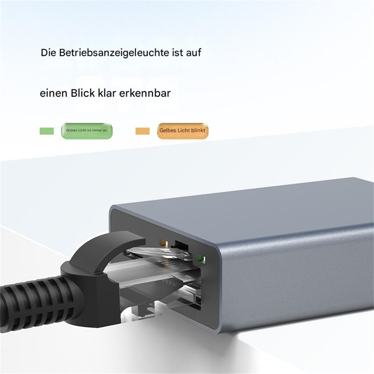 Grauer Adapter mit schwarzem Kabel. Grüne und orangefarbene Lichter zeigen den Status an.