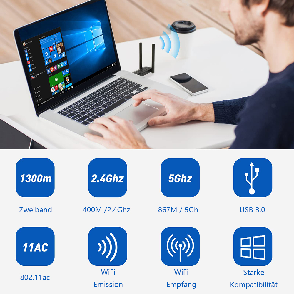 Eine Person benutzt einen Laptop mit WLAN-Adapter, neben einer Kaffeetasse und einem Telefon auf einem weißen Schreibtisch.