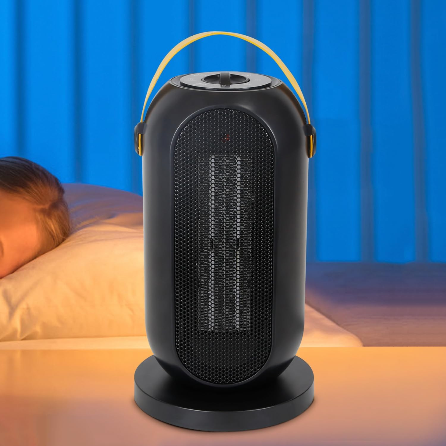 Schwarzer Elektroheizer neben einem Bett mit schlafender Person, mit gelbem Griff oben.