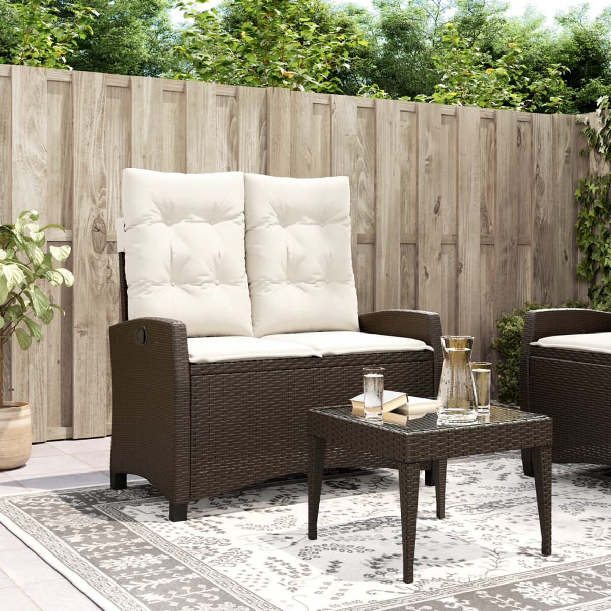 Set patio esterno con divano e tavolo. Cuscini beige, vimini marrone scuro e tappeto fantasia.