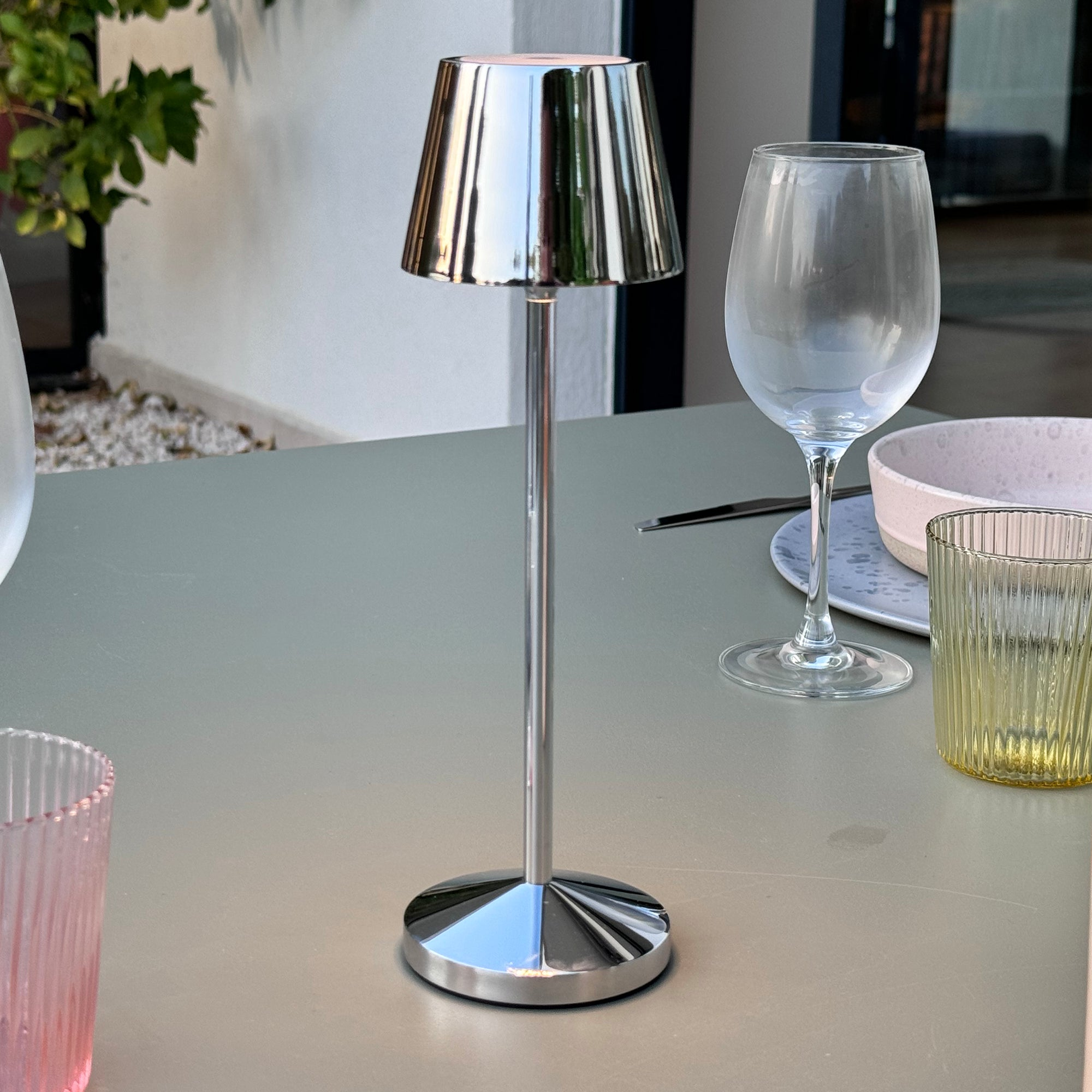 Tischlampe mit silbernem Fuß und Schirm, neben einem Weinglas.