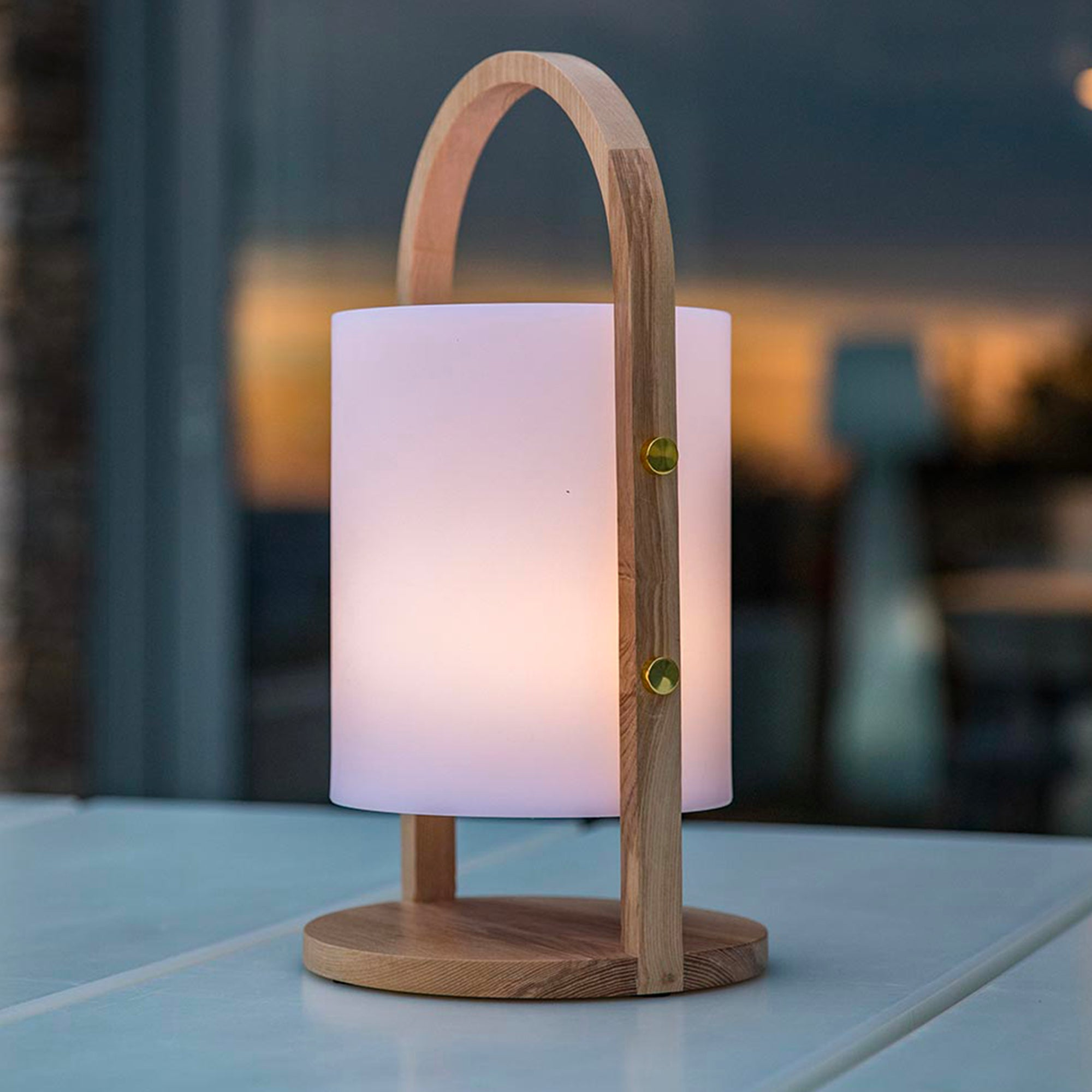 Eine Holztischlampe mit weißem, beleuchtetem Schirm und einem gebogenen Holzgriff.