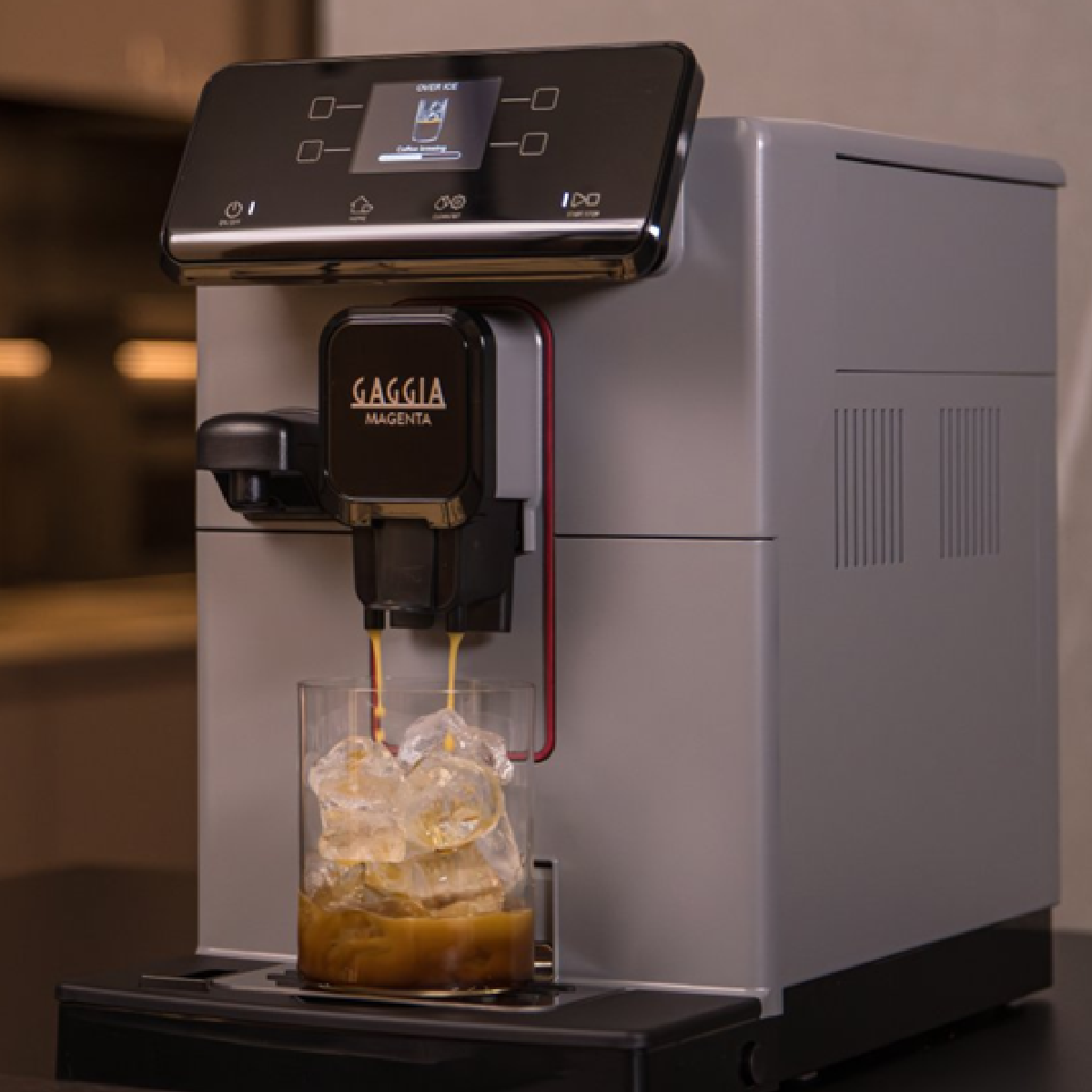 Eine silberne und schwarze Gaggia Magenta Espressomaschine gibt Espresso in ein Glas mit Eiswürfeln aus.