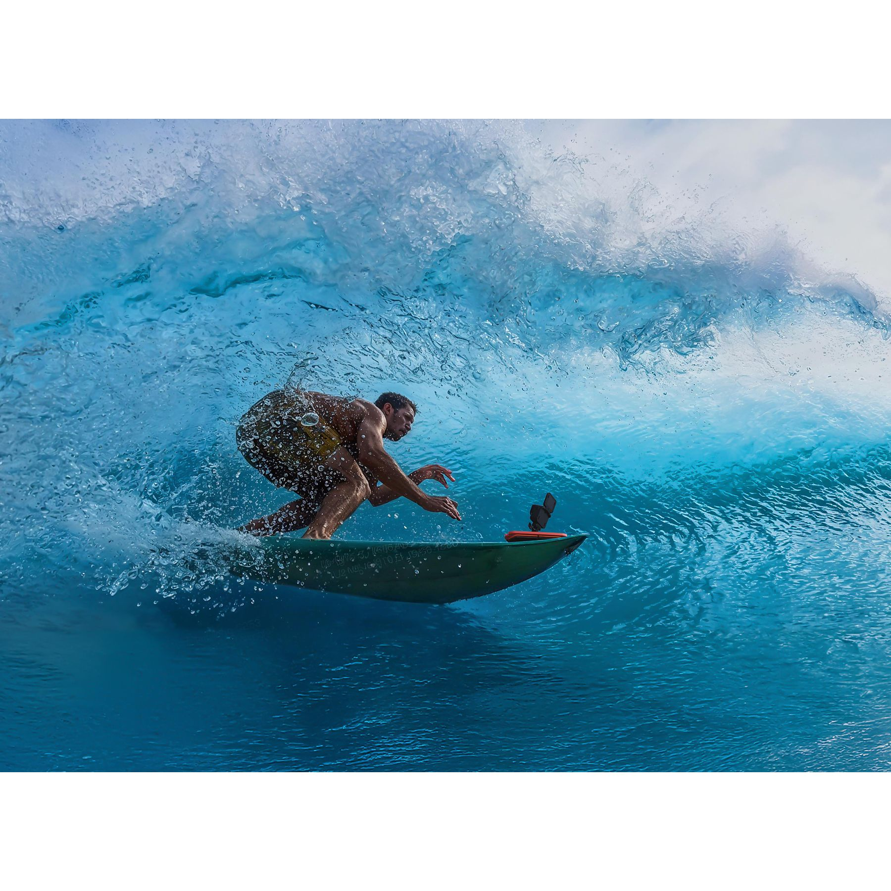 Surfer na zielonej desce surfingowej jadący na dużej fali. Błękitny ocean i niebo.