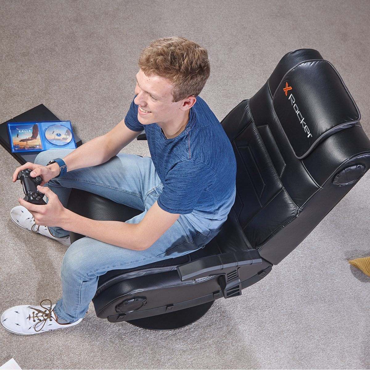 Ein junger Mann in einem Gaming-Stuhl, der einen Controller hält, Spiel-CDs in der Nähe.