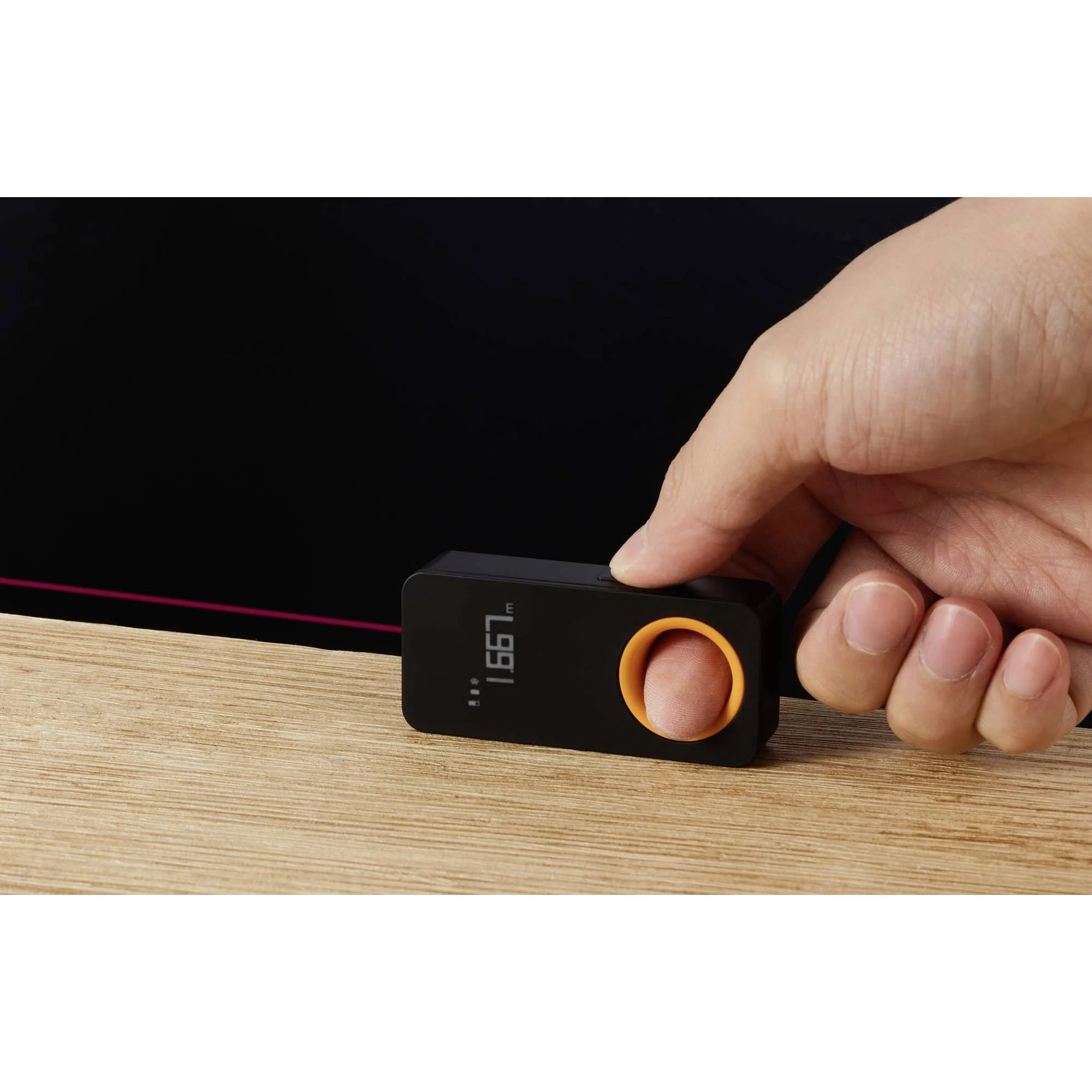 Eine Hand, die ein schwarzes Messgerät mit Laserpointer hält.
