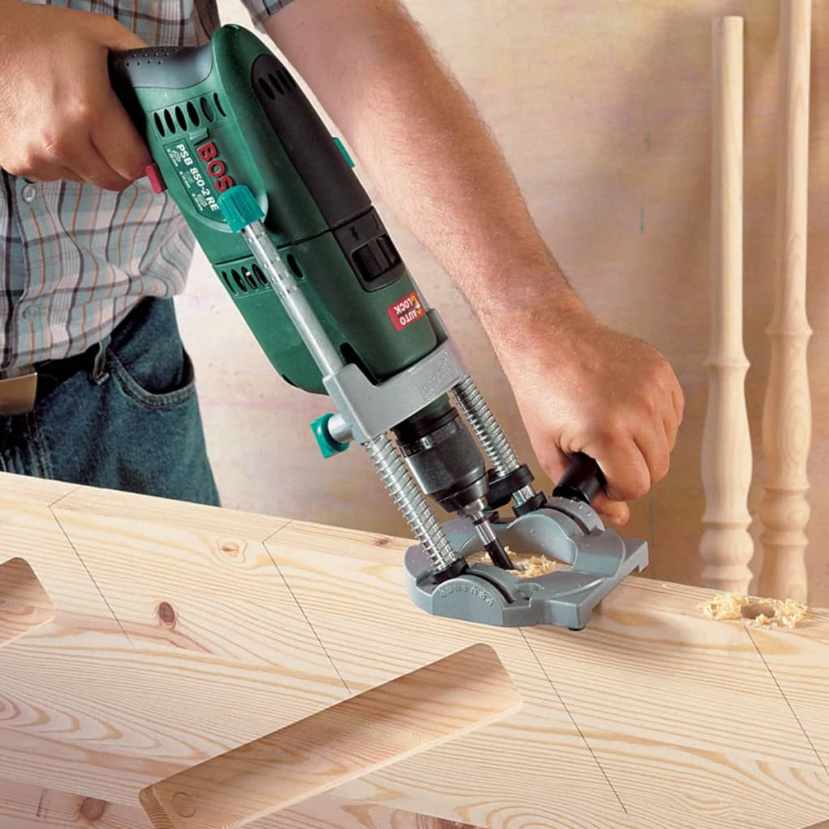 Uomo che usa un trapano verde e nero sul legno, con pezzi di legno e balaustre.