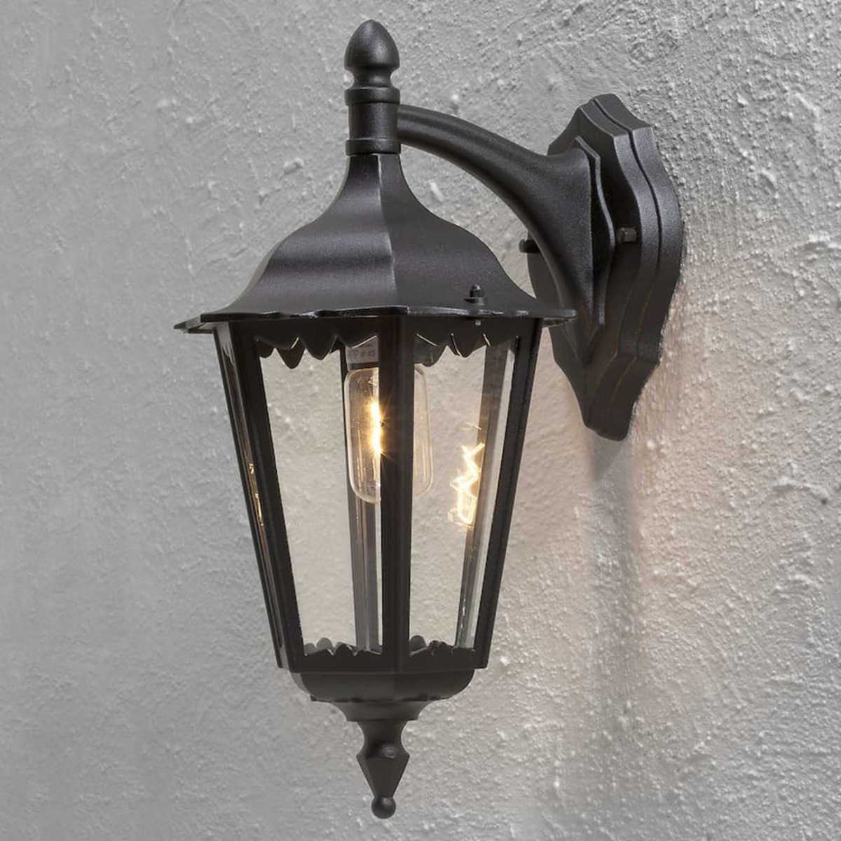 Schwarze Außenwandleuchte. Glasscheiben, Glühbirne sichtbar.