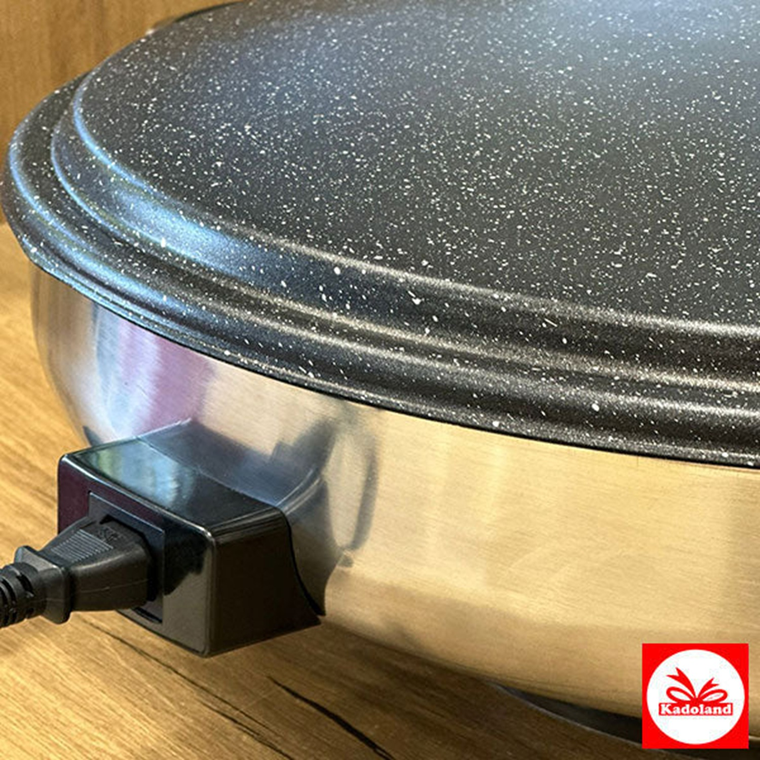 A close-up of a speckled black griddle with an attached power cord.