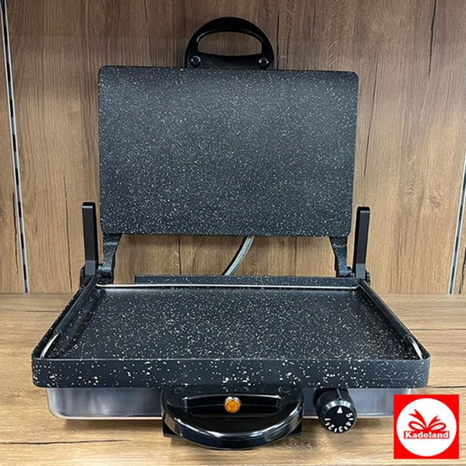 A black and grey panini press with a red logo on a wooden surface.
