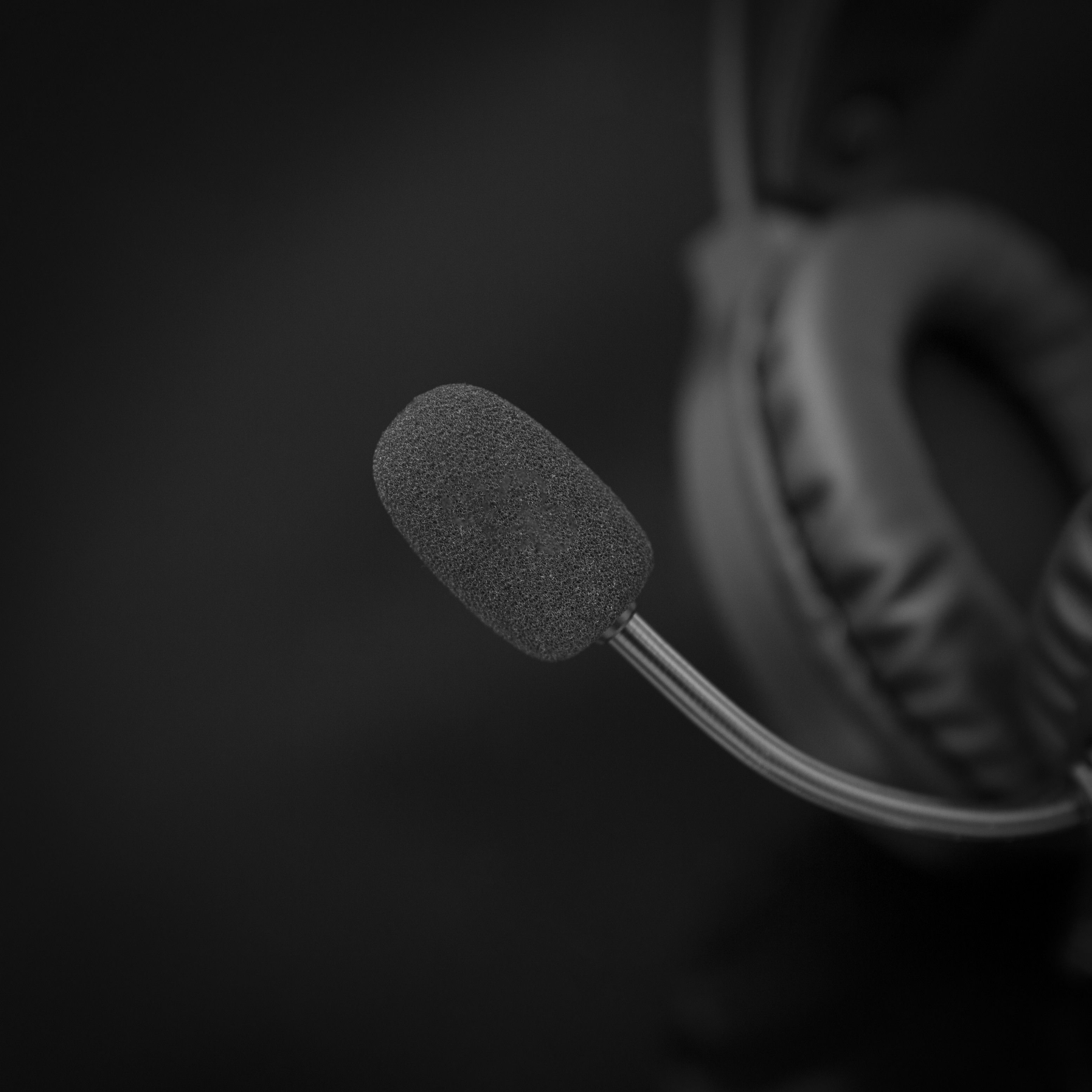 Primo piano di un microfono e cuffie neri, immagine monocromatica.