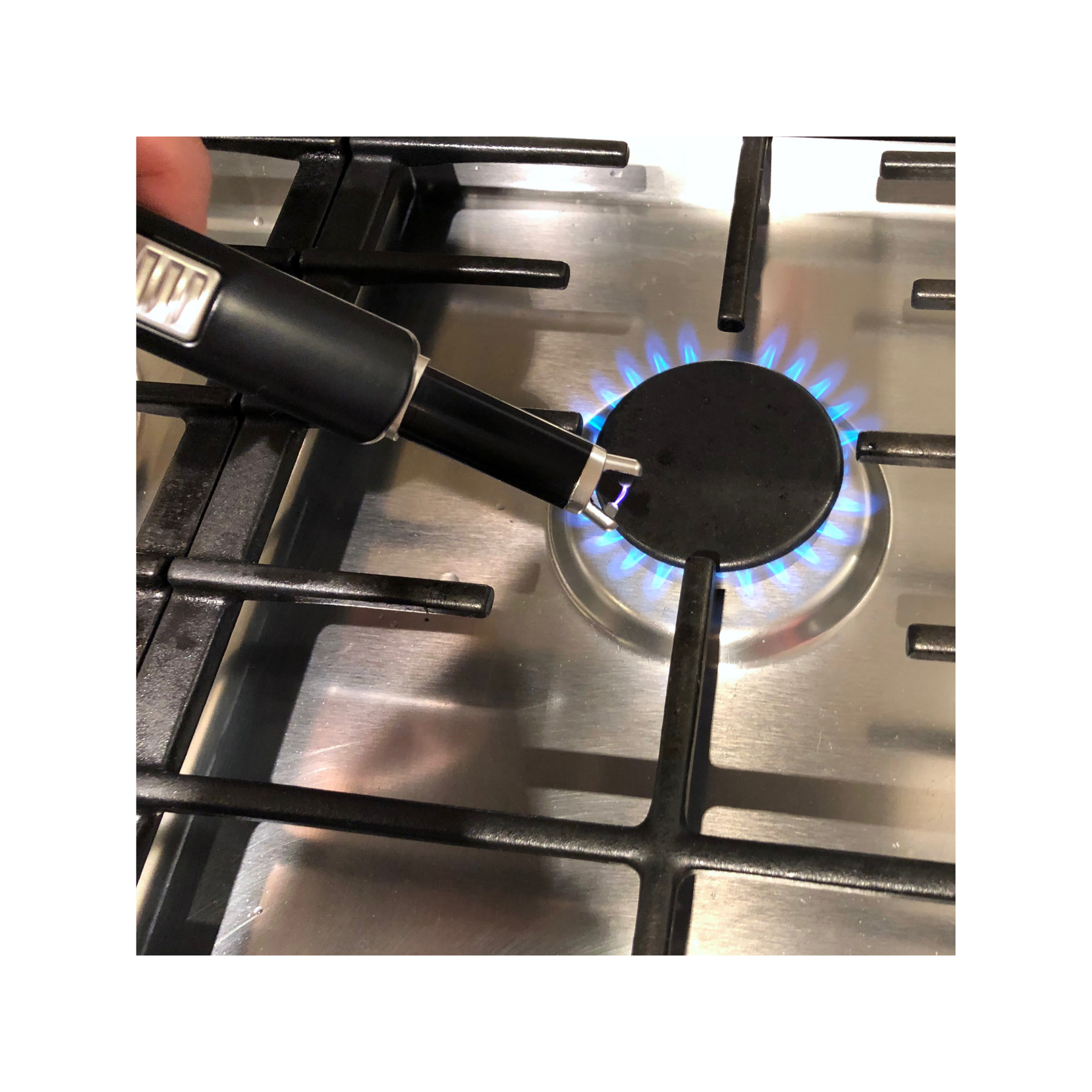 Ein Gasherd-Brenner mit blauen Flammen. Ein schwarzes Feuerzeug wird über dem Brenner gehalten.