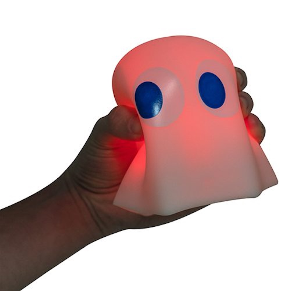 Een spookvormige lamp in een hand. De lamp is roze met blauwe ogen. Witte achtergrond.