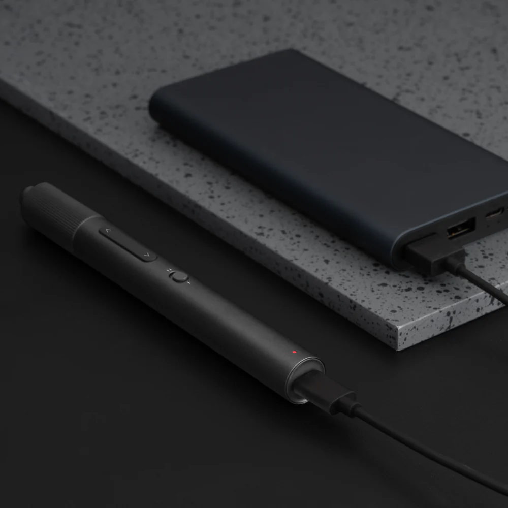 Un telecomando per presentazioni nero collegato a un power bank con un cavo USB.