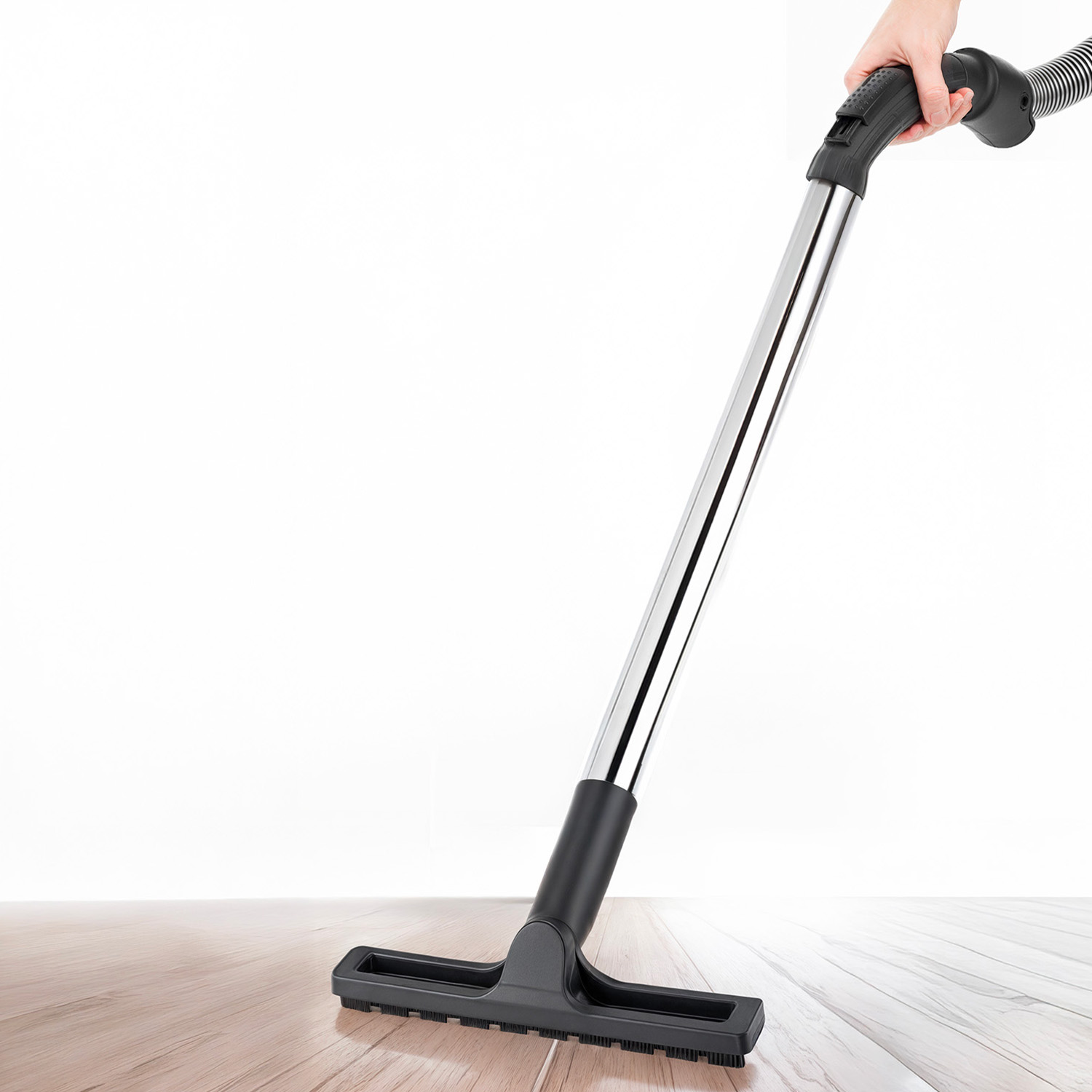 Una mano che tiene l'aspirapolvere e pulisce il pavimento in legno.