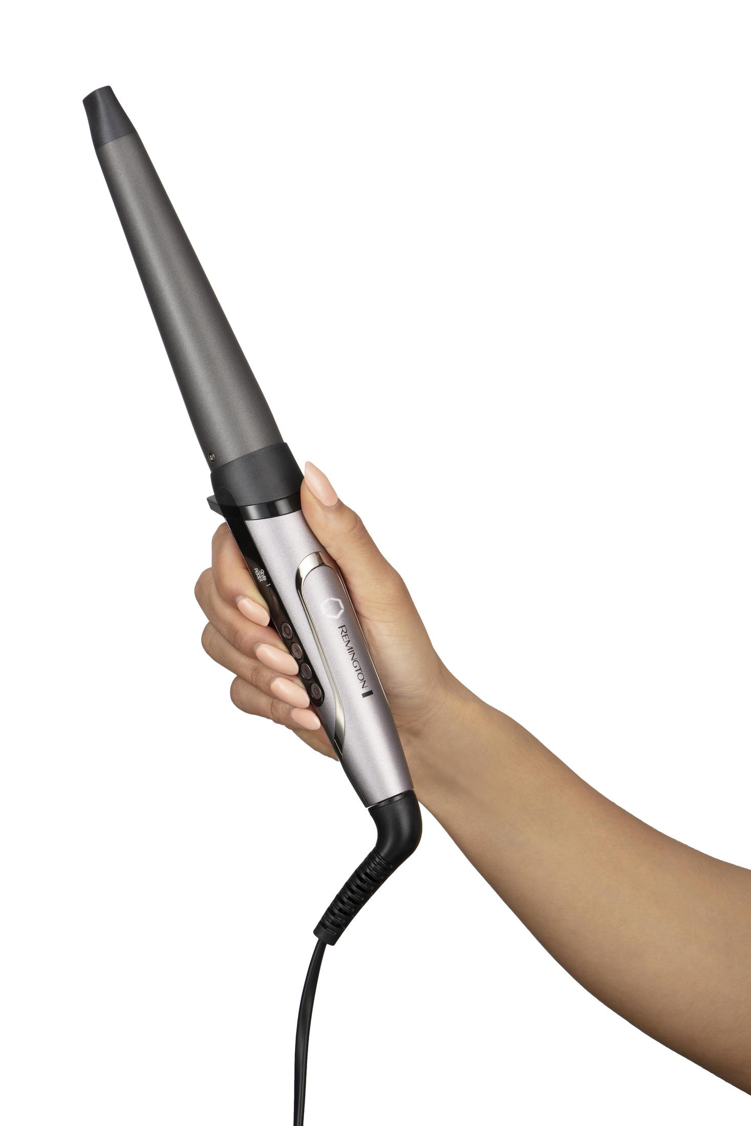 Dłoń trzymająca srebrną lokówkę. Białe tło.