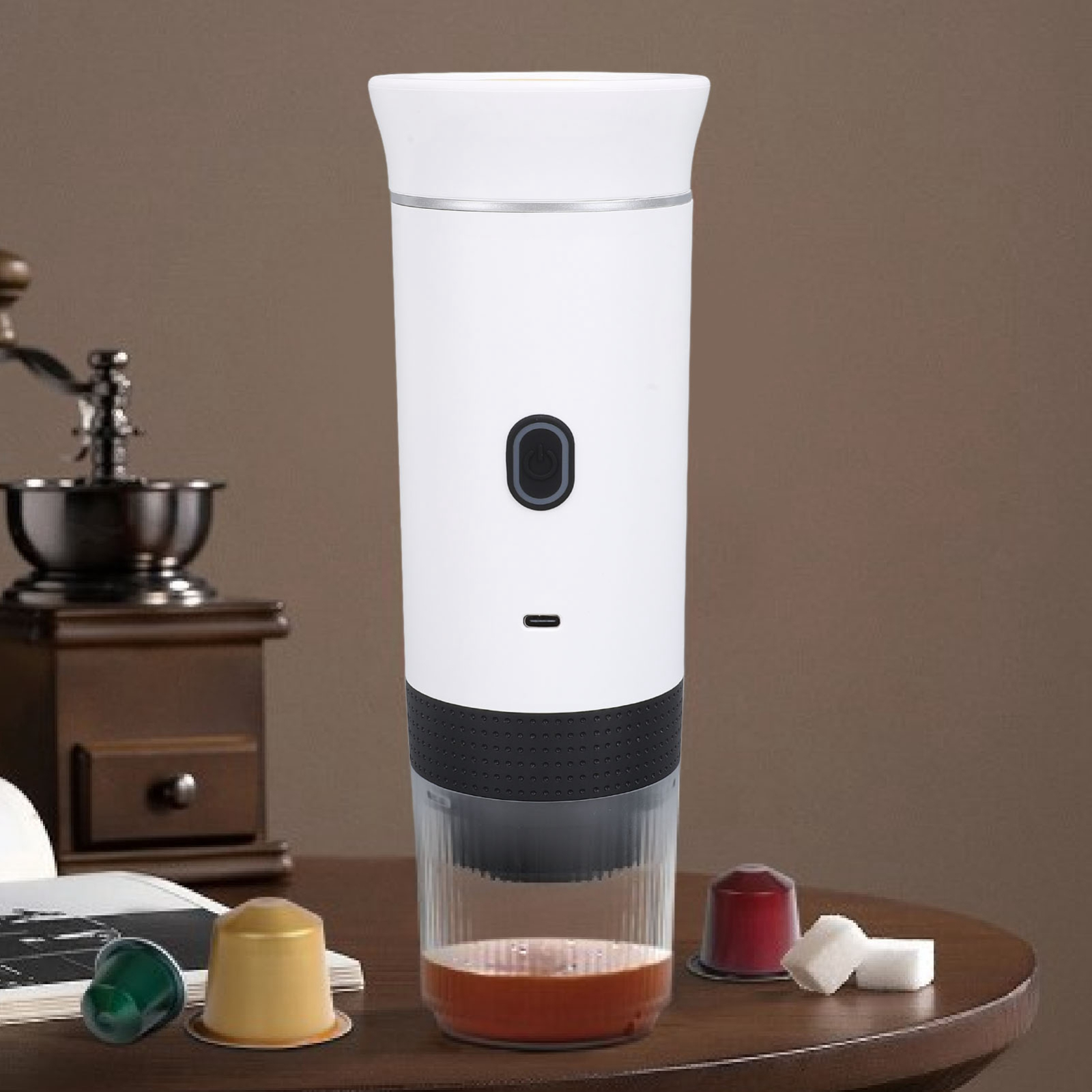 Eine weiße Kaffeemaschine mit einem durchsichtigen Becher. Kaffeekapseln und Würfelzucker.