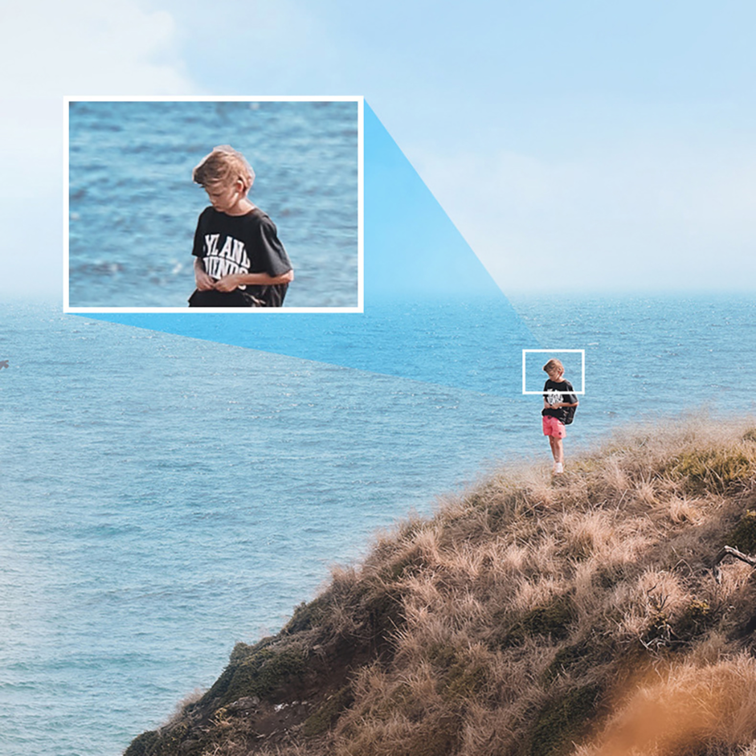 Ein Junge steht auf einem Hügel mit Blick auf das Meer. Das Bild ist vergrößert.