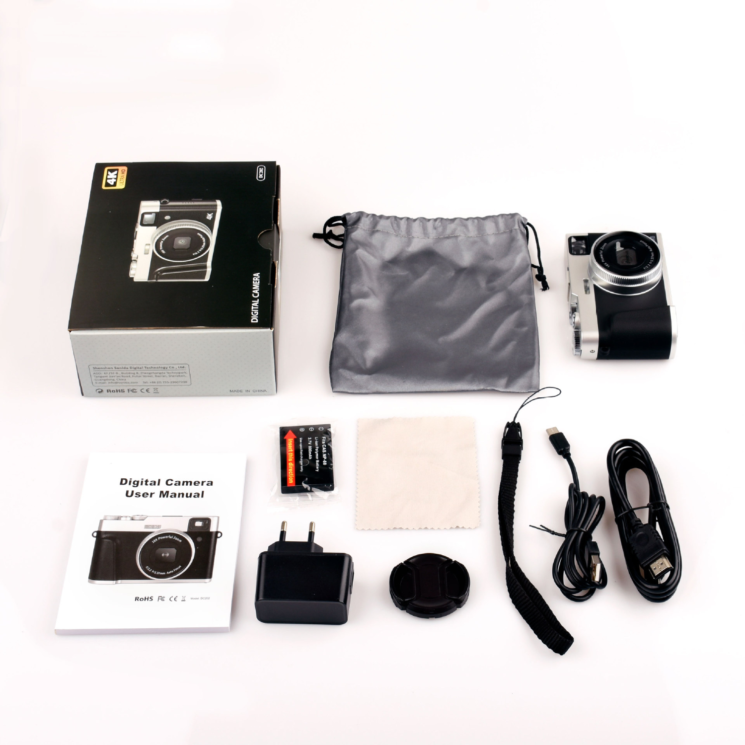 Kamera-Kit: Kamera, Karton, Tasche, Handbuch, Ladegerät, Kappe, Kabel und Zubehör auf weißer Oberfläche.