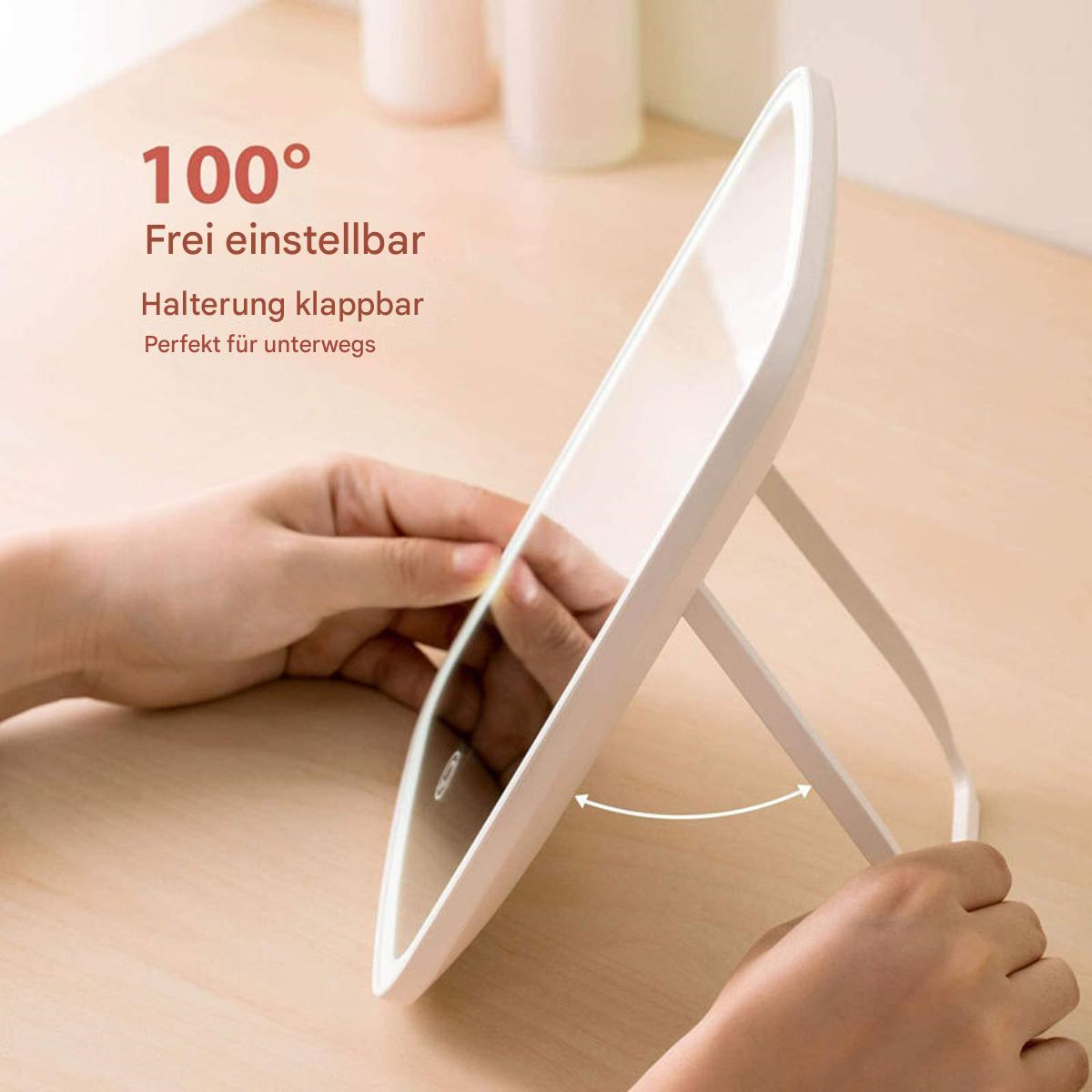 Ein weiß gerahmter Spiegel, verstellbar auf einem Ständer, auf einem Holztisch platziert. Hände sind sichtbar.