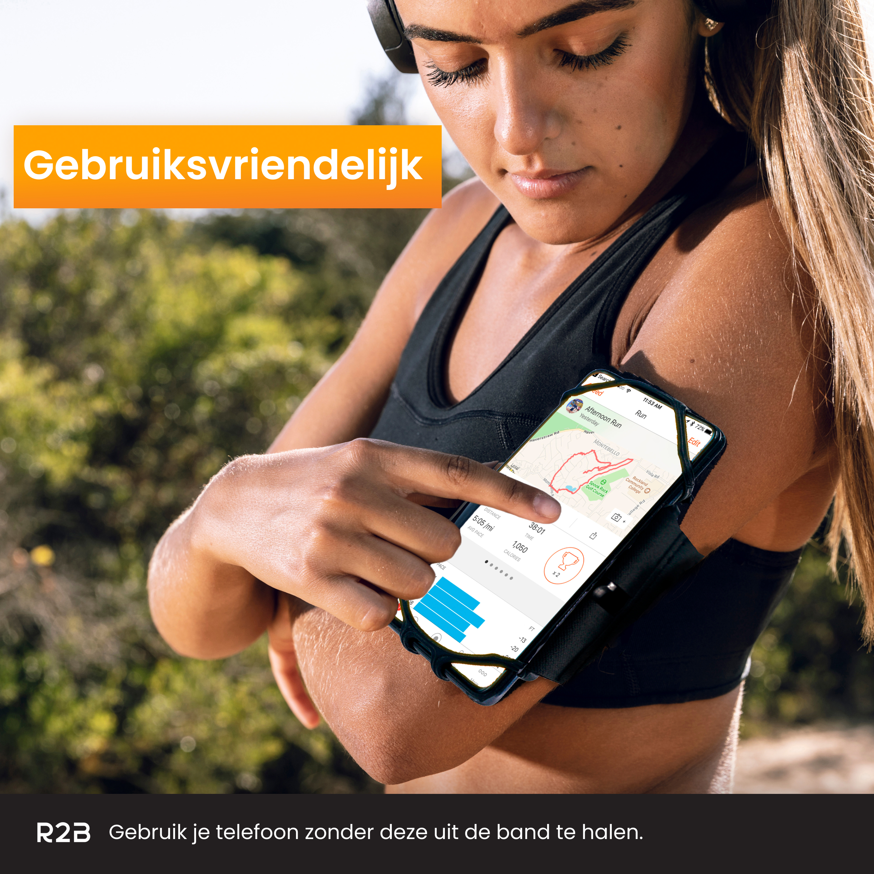 Frau benutzt Handy am Armband beim Laufen. Grüner Hintergrund, sonniger Tag. Schwarzes Band, Handy sichtbar.