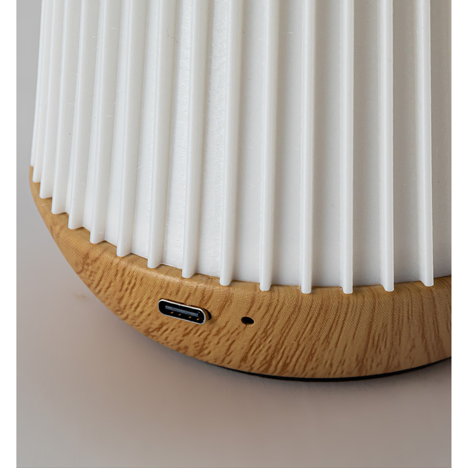 Nahaufnahme eines Lampensockels mit Holzmaserung und USB-Anschluss. Holzsockel mit weißer Lampe.